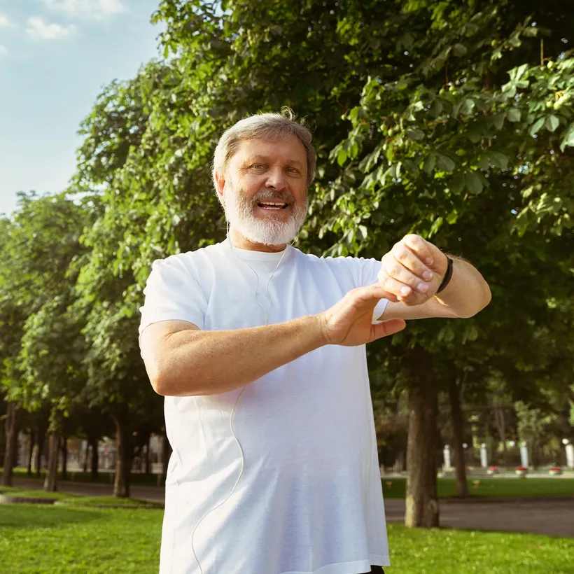 Active older man checking his fitness tracker after a walk in the park